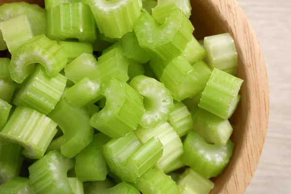 Fresh cut celery stalks in bowl on wooden table, top view