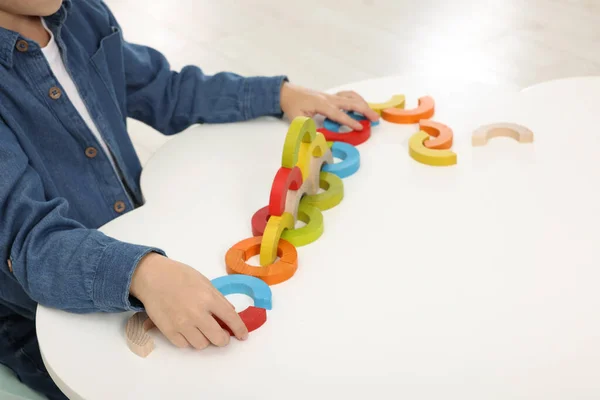 Motor skills development. Boy playing with colorful wooden arcs at white table, closeup. Space for text