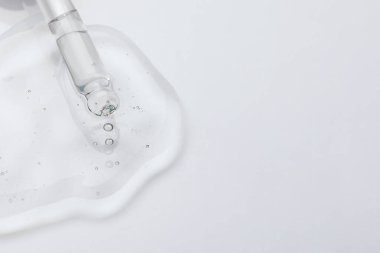 Pipetten ışık yüzeyine kozmetik yağ damlatıyor, yakın plan. Metin için boşluk