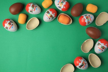 Sveti Vlas, Bulgaristan - 29 Haziran 2023: Yeşil zemin üzerinde Kinder Surprise Eggs ve plastik kapsüller, düz zemin. Metin için boşluk