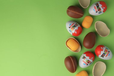 Sveti Vlas, Bulgaristan - 29 Haziran 2023: Açık yeşil zemin üzerinde Kinder Surprise Eggs ve plastik kapsüller, düz zemin. Metin için boşluk