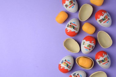 Sveti Vlas, Bulgaristan - 29 Haziran 2023: Mor arka planda Kinder Sürpriz Yumurtalar ve plastik kapsüller, düz konum. Metin için boşluk