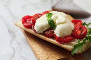 Lezzetli burrata peynirli tost, domates ve roka beyaz mermer masada, yakın plan. Metin için boşluk