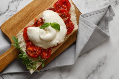 Lezzetli burrata peynirli tost, domates ve roka beyaz mermer masa, üst görünüm