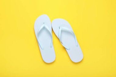 Sarı arka planda şık beyaz parmak arası terlikler, üst görünüm