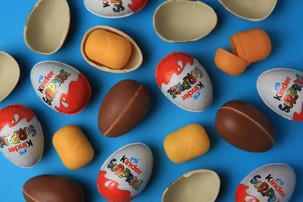 Sveti Vlas, Bulgaristan - 29 Haziran 2023: Açık mavi zemin üzerinde Kinder Sürpriz Yumurtalar ve plastik kapsüller, düz yatar