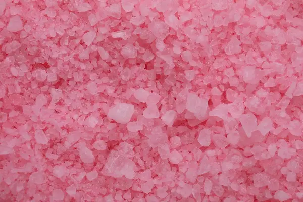 Pink sea salt as background, top view