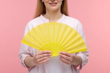 Pembe arka planda sarı elli kadın, yakın plan.