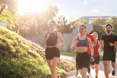 Güneşli bir günde dışarıda koşan bir grup insan.