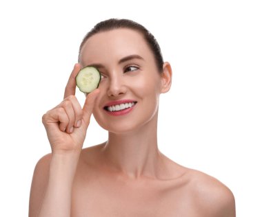 Güzel bir kadın beyaz arka planda bir parça salatalıkla gözlerini kapatıyor.