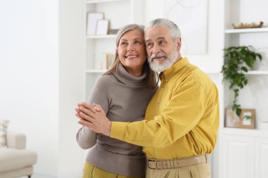 Sevecen yaşlı çift evdeki oturma odasında dans ediyor.