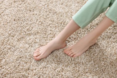 Evdeki yumuşak, açık kahverengi halıda bir kadın, yakın plan. Metin için boşluk