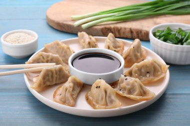 Lezzetli gyoza (Asya hamur tatlısı), soya sosu ve çubuklar açık mavi ahşap masa üzerinde, yakın plan