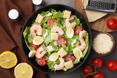 Kahverengi masa üzerinde karides ve malzemelerle nefis Sezar salatası.