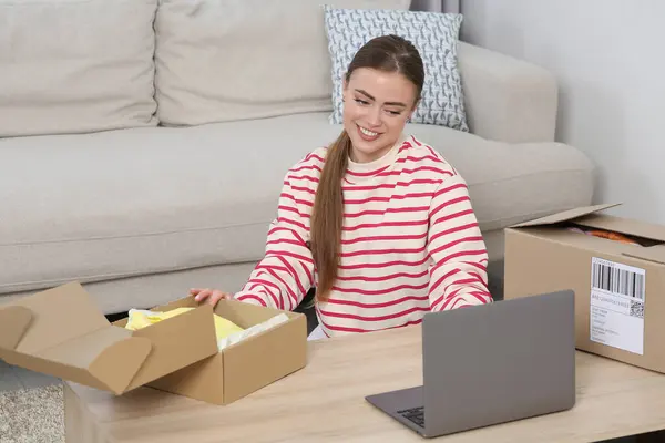 Happy woman with laptop and parcel at home. Online store