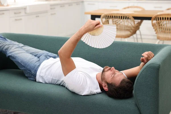 Man Waving White Hand Fan Cool Himself Sofa Home — Stock Photo, Image