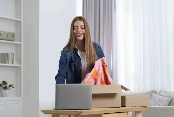 Happy woman unpacking parcel at home. Online store