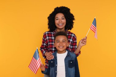 4 Temmuz - ABD 'nin Bağımsızlık Günü. Sarı arka planda Amerikan bayrakları olan mutlu kadın ve oğlu.