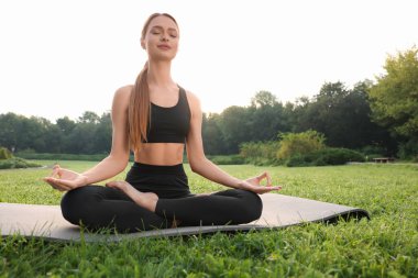 Güzel genç bir kadın yoga minderinde Padmasana egzersizi yapıyor. Lotus pozu