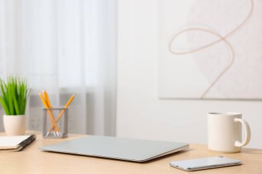 Merkez ofis. Laptop, akıllı telefon, kupa ve kırtasiye malzemeleri kapalı bir masa içinde. Metin için boşluk
