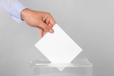 Adam oyunu açık gri arka planda sandığa koyuyor, yakın plan.