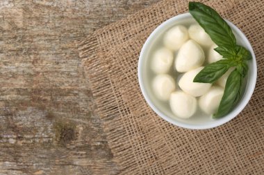Lezzetli mozzarella topları ve fesleğen yaprakları ahşap masada, üst tarafta. Metin için boşluk
