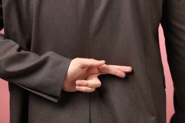 Pembe arka planda parmaklarını çapraz yapan adam, yakın plan ve arka plan