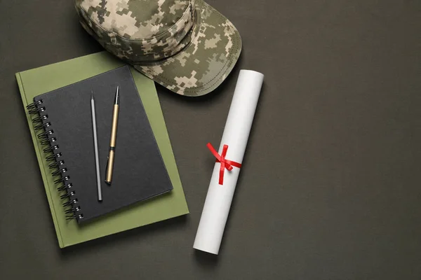 Stationery, soldier cap and diploma on dark background, flat lay with space for text. Military education