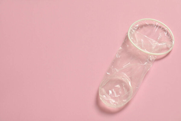 Unrolled female condom on light pink background, top view and space for text. Safe sex