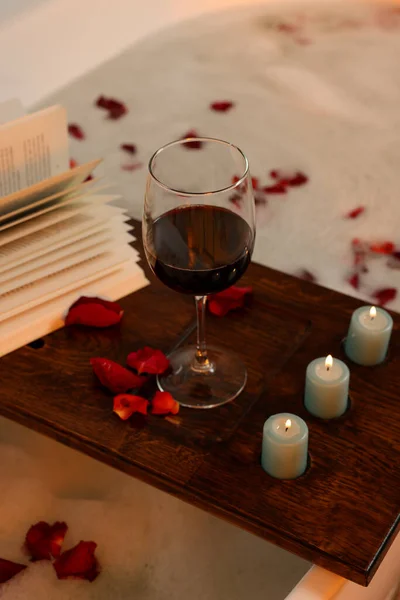 木制木板 上有酒杯 燃烧的蜡烛和玫瑰花瓣 — 图库照片