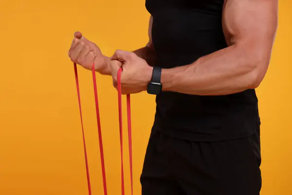 Young Man Exercising Elastic Resistance Band Orange Background Closeup — Stock Photo, Image