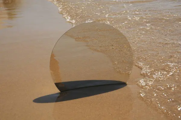 在沙滩上反射大海的圆形镜子 — 图库照片