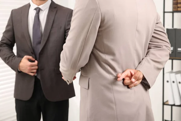 stock image Employee crossing fingers behind his back while shaking hands with boss in office, closeup