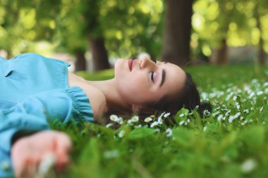 Parktaki yeşil çimlerin üzerinde yatan güzel bir kadın. Bahar güneşli gün
