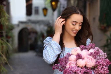 Açık havada bir buket bahar çiçeğiyle güzel bir kadın.
