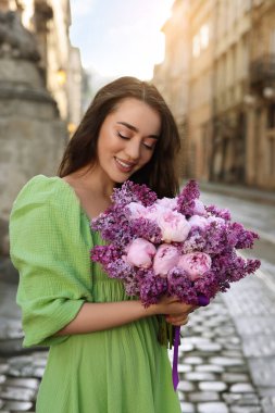 Şehir caddesinde elinde bir buket bahar çiçeğiyle güzel bir kadın.