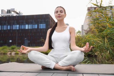 Güzel bir genç kadın yoga minderinde Padmasana egzersizi yapıyor. Lotus pozu