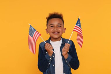 4 Temmuz - ABD 'nin Bağımsızlık Günü. Sarı arka planda Amerikan bayrakları olan mutlu çocuk.