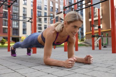 Spor salonunda tahta egzersizi yapan bir kadın.