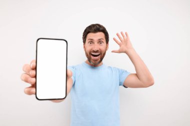 Beyaz arka planda akıllı telefon gösteren şaşırtıcı bir adam.