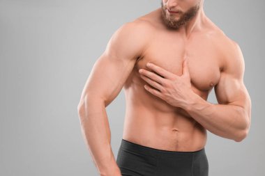 Açık gri arka planda karın kasları gösteren kaslı bir adam, yakın plan ve mesaj için boşluk. Seksi vücut.