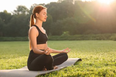 Güzel genç bir kadın yoga minderinde Padmasana egzersizi yapıyor, mesaj için yer var. Lotus pozu