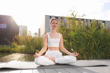 Güzel genç bir kadın yoga minderinde Padmasana egzersizi yapıyor. Lotus pozu