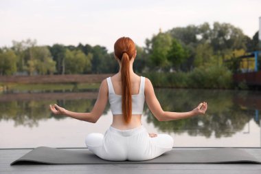 Dışarıdaki yoga minderinde Padmasana egzersizi yapan bir kadın. Lotus pozu