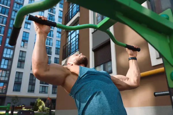 Man doing pull ups at outdoor gym, low angle view