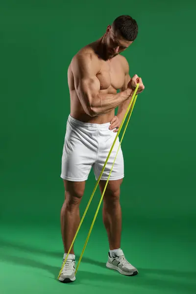 Muskulöser Mann Trainiert Mit Elastischem Widerstandsband Auf Grünem Hintergrund — Stockfoto