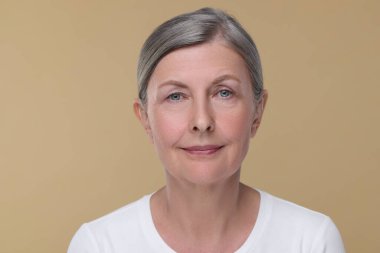 Bej arka planda yaşlanmakta olan yaşlı bir kadının portresi. Yenilenme tedavisi