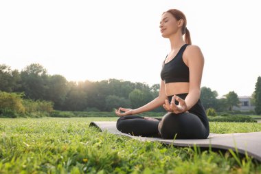 Güzel genç bir kadın yoga minderinde Padmasana egzersizi yapıyor. Düşük açılı görüş ve mesaj için yer. Lotus pozu