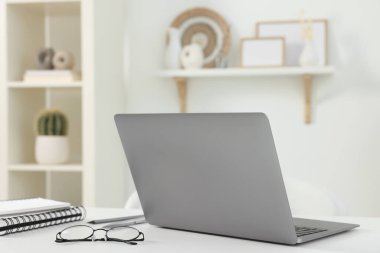Merkez ofis. Laptop, gözlük ve kırtasiye malzemeleri beyaz masa içinde.