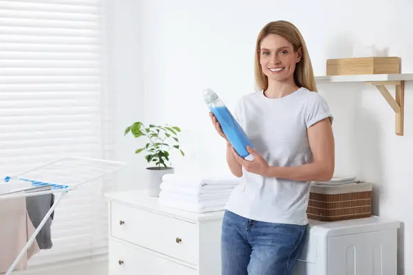 Woman holding fabric softener in bathroom, space for text